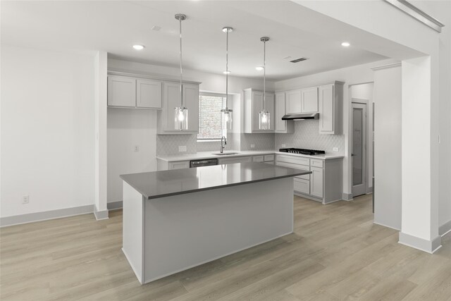 kitchen with stainless steel appliances, pendant lighting, backsplash, light hardwood / wood-style floors, and a kitchen island