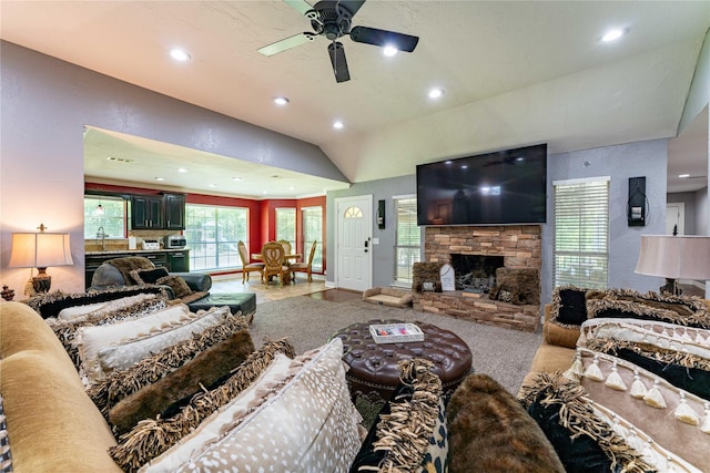 living room featuring ceiling fan, lofted ceiling, a fireplace, and sink