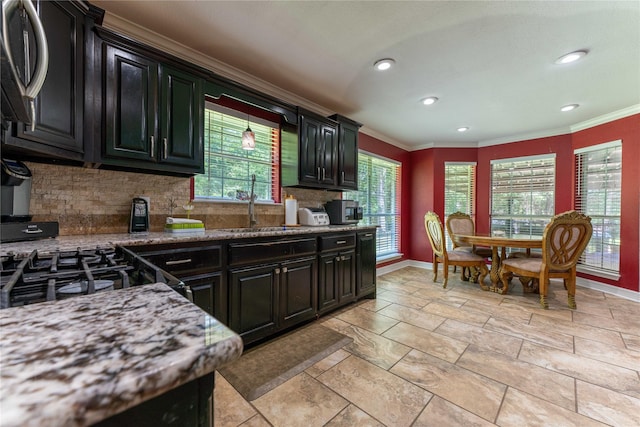 kitchen featuring stone counters, ornamental molding, tasteful backsplash, and sink