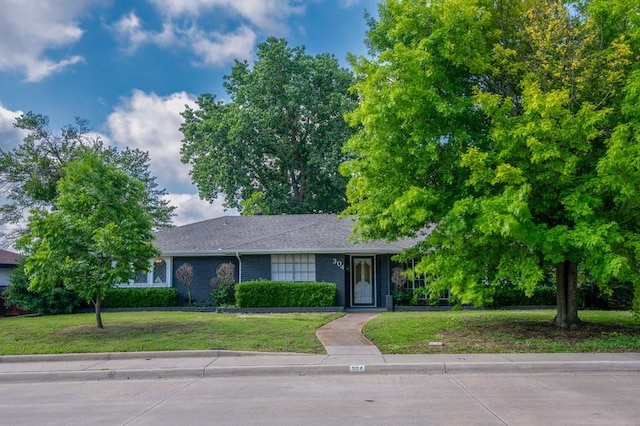 view of front of house with a front lawn, brick siding, and roof with shingles