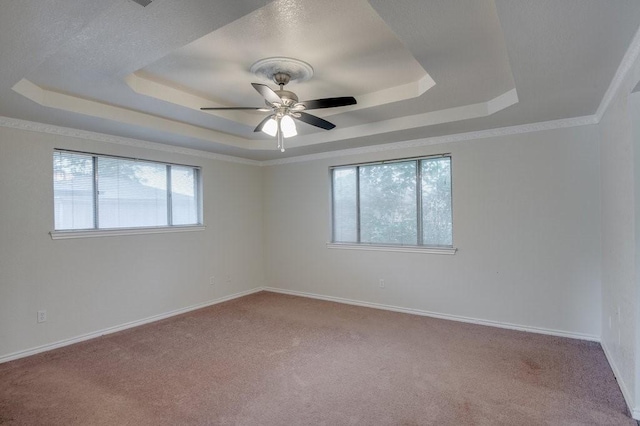 carpeted spare room with ceiling fan, a tray ceiling, and crown molding