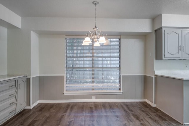 unfurnished dining area with an inviting chandelier and dark hardwood / wood-style flooring