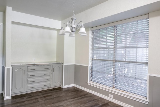 unfurnished dining area featuring an inviting chandelier and dark hardwood / wood-style flooring