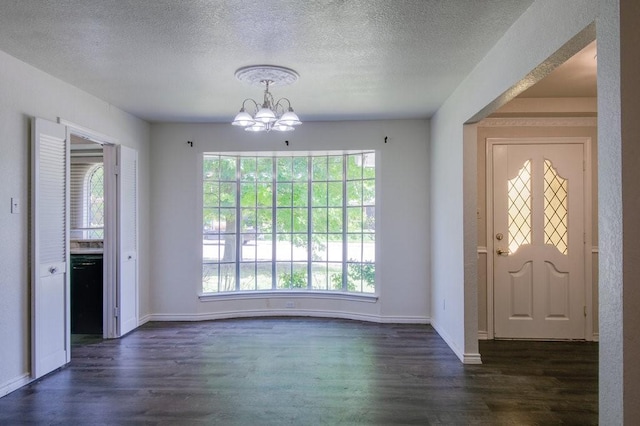 entrance foyer featuring a textured ceiling, dark hardwood / wood-style flooring, and an inviting chandelier