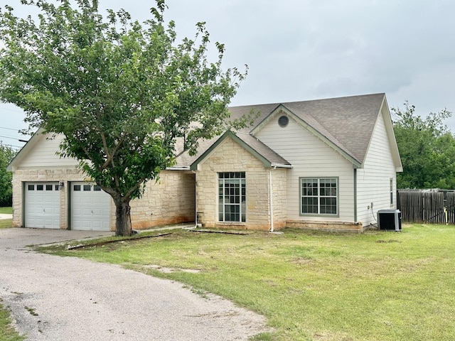 ranch-style home featuring a front lawn, a garage, and central AC