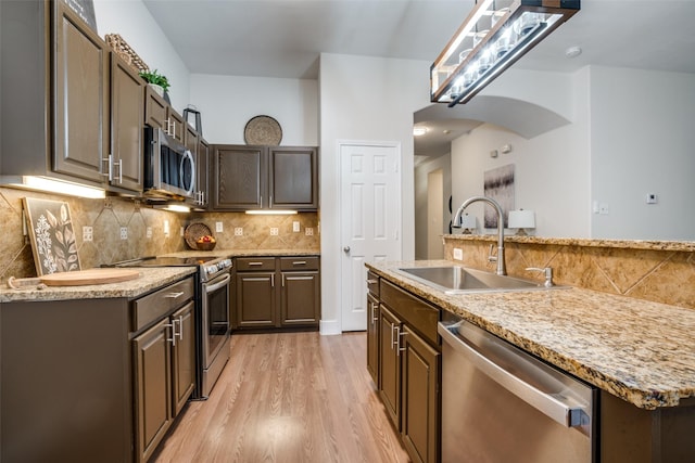 kitchen featuring an island with sink, appliances with stainless steel finishes, sink, and dark brown cabinetry