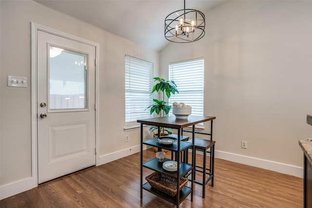 dining area with hardwood / wood-style flooring, lofted ceiling, and a notable chandelier