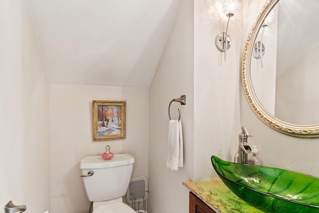 bathroom featuring vanity, toilet, and vaulted ceiling