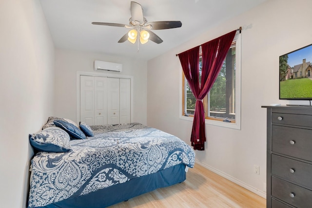 bedroom with ceiling fan, an AC wall unit, light hardwood / wood-style flooring, and a closet