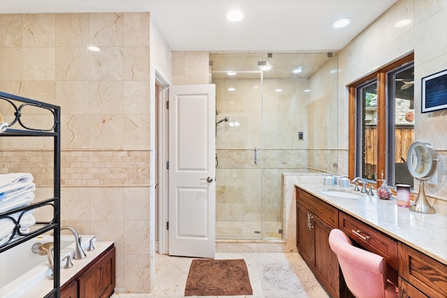 bathroom featuring plus walk in shower, vanity, tile patterned floors, and tile walls