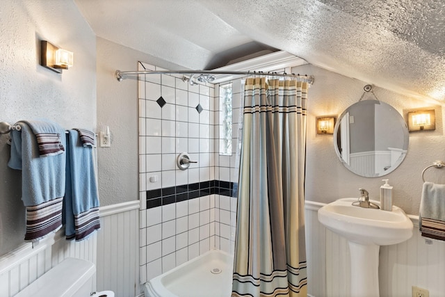 bathroom with a shower with curtain, toilet, lofted ceiling, and a textured ceiling