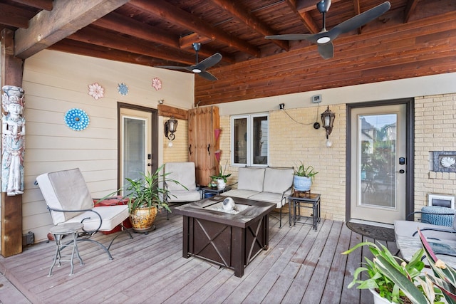 wooden deck featuring ceiling fan and an outdoor living space with a fire pit