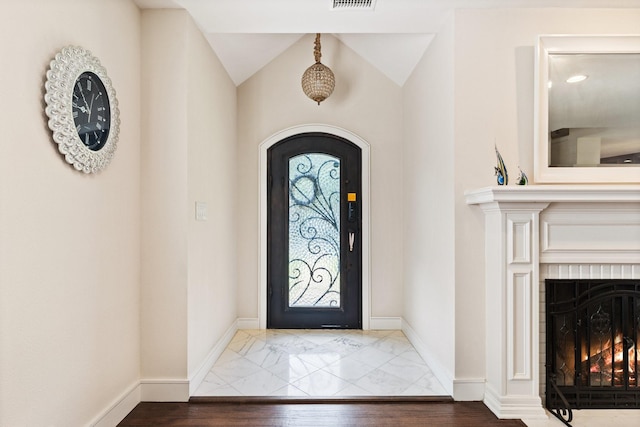 foyer entrance with vaulted ceiling and a fireplace