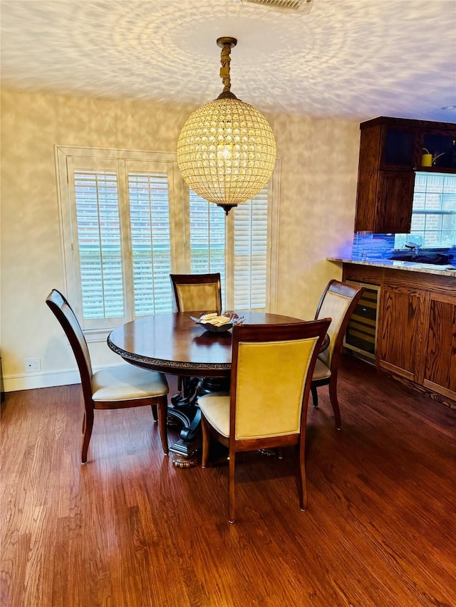 dining area with beverage cooler, wood-type flooring, and a textured ceiling