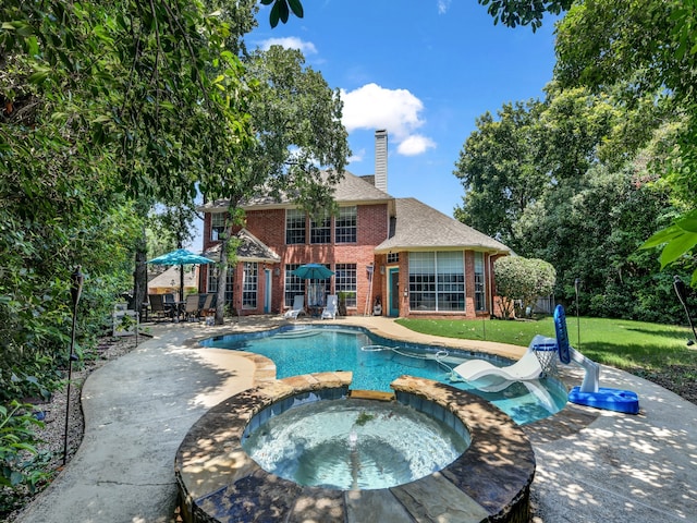 view of pool with a lawn, a patio area, and an in ground hot tub