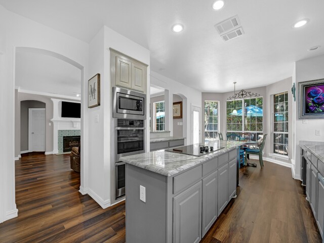 kitchen with dark wood-type flooring, stainless steel appliances, a kitchen island, and gray cabinetry