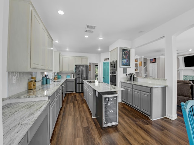 kitchen featuring appliances with stainless steel finishes, dark hardwood / wood-style flooring, gray cabinets, and beverage cooler