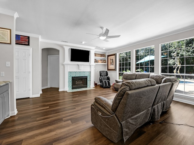 living room featuring a fireplace, dark hardwood / wood-style floors, ceiling fan, and crown molding