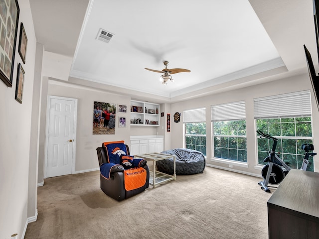 interior space with a raised ceiling, ceiling fan, crown molding, and light colored carpet