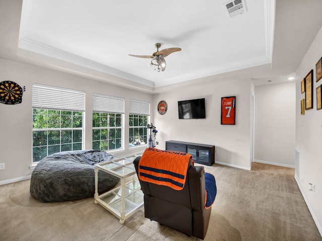 carpeted living room with a raised ceiling, ceiling fan, a healthy amount of sunlight, and ornamental molding