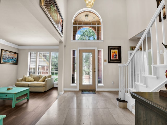 entryway with a high ceiling, light wood-type flooring, and an inviting chandelier