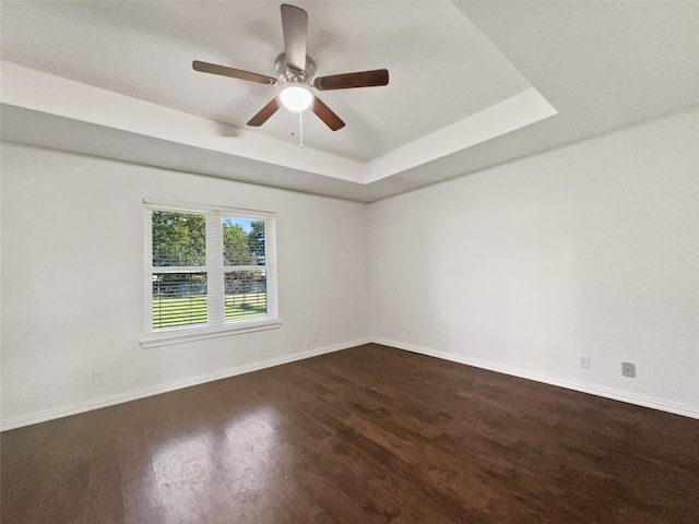 spare room featuring ceiling fan, dark hardwood / wood-style flooring, and a tray ceiling