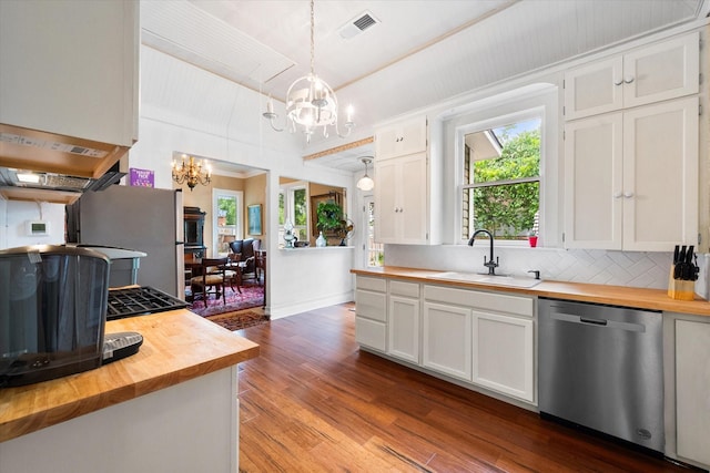 kitchen featuring appliances with stainless steel finishes, wood counters, white cabinetry, and decorative light fixtures