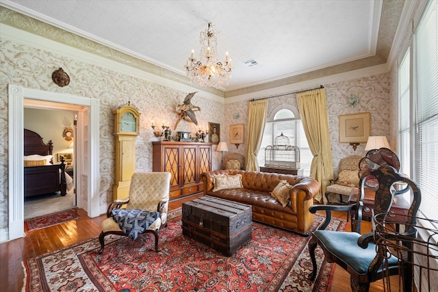 living area with hardwood / wood-style floors, ornamental molding, and an inviting chandelier