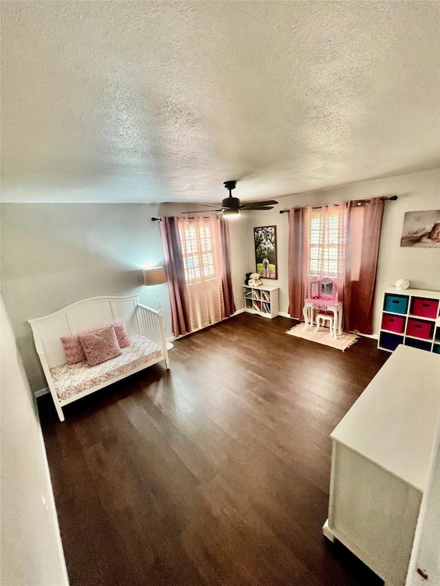 unfurnished bedroom with ceiling fan, dark hardwood / wood-style flooring, and a textured ceiling