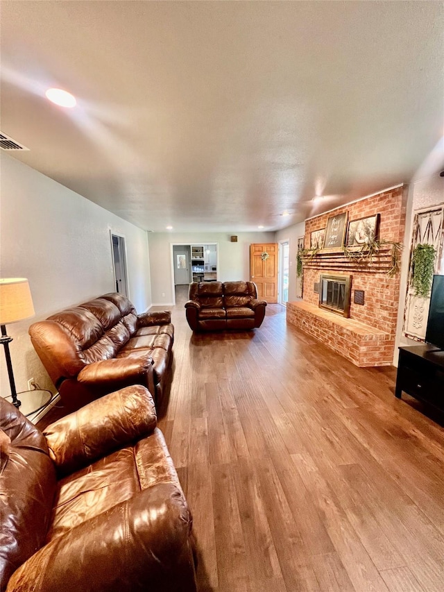 living room with a brick fireplace and hardwood / wood-style flooring