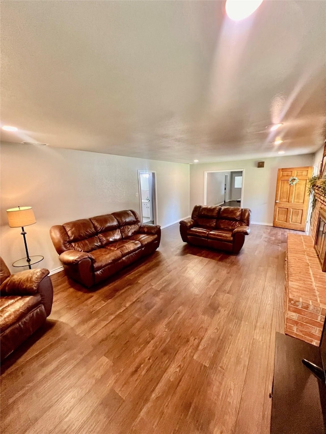 living room with wood-type flooring and a brick fireplace