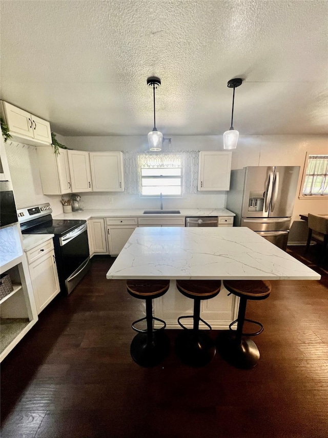 kitchen featuring white cabinets, pendant lighting, stainless steel appliances, and sink