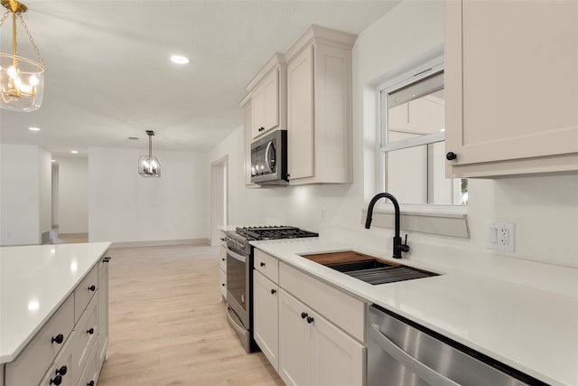 kitchen featuring pendant lighting, light hardwood / wood-style flooring, stainless steel appliances, and sink