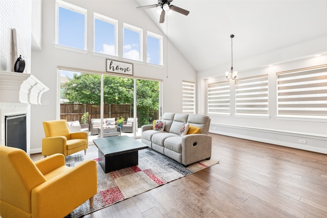 living room with ceiling fan with notable chandelier, wood-type flooring, and a high ceiling