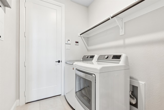 clothes washing area featuring light tile patterned floors and washing machine and clothes dryer