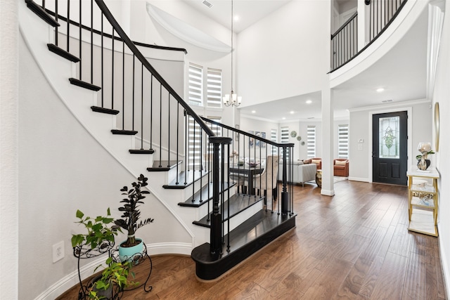 entrance foyer featuring a notable chandelier, wood-type flooring, crown molding, and a high ceiling