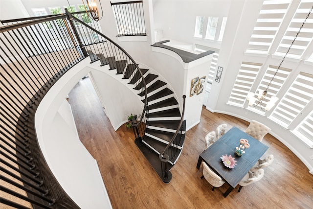 stairs featuring hardwood / wood-style flooring, a notable chandelier, and a wealth of natural light