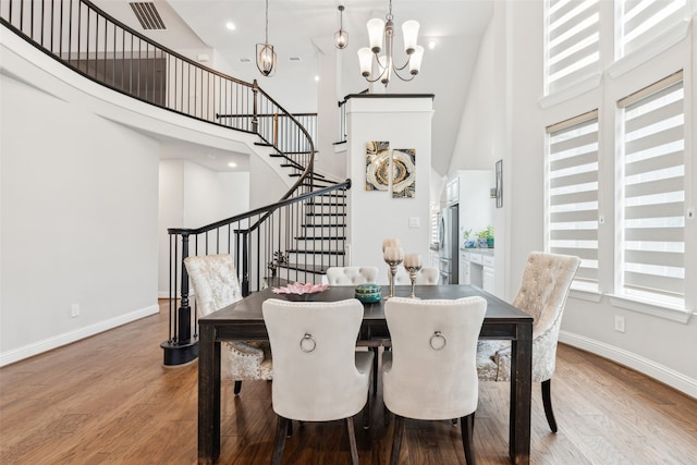 dining room featuring hardwood / wood-style floors, a notable chandelier, and a towering ceiling