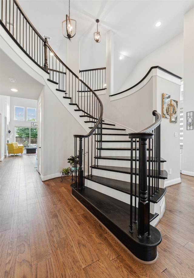 staircase with a high ceiling and wood-type flooring