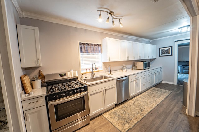 kitchen with hardwood / wood-style floors, sink, white cabinets, and stainless steel appliances