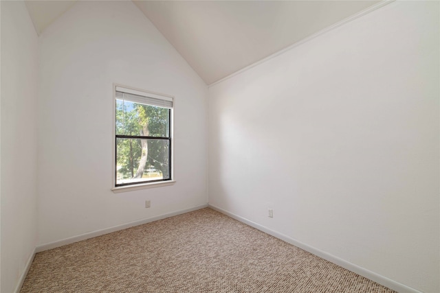 carpeted spare room featuring vaulted ceiling