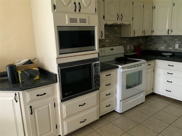 kitchen with light tile patterned floors, white cabinetry, backsplash, electric range, and black microwave