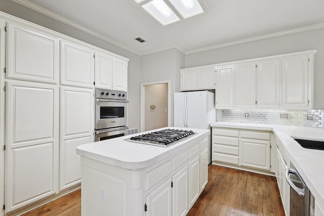 kitchen with dark hardwood / wood-style flooring, white cabinets, appliances with stainless steel finishes, and a kitchen island