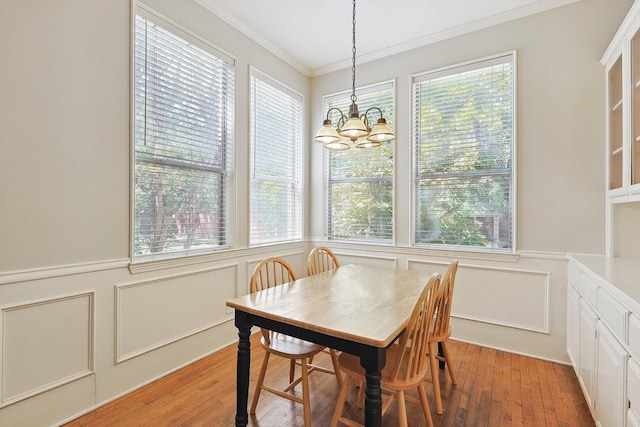 dining space featuring light hardwood / wood-style flooring, a chandelier, and ornamental molding