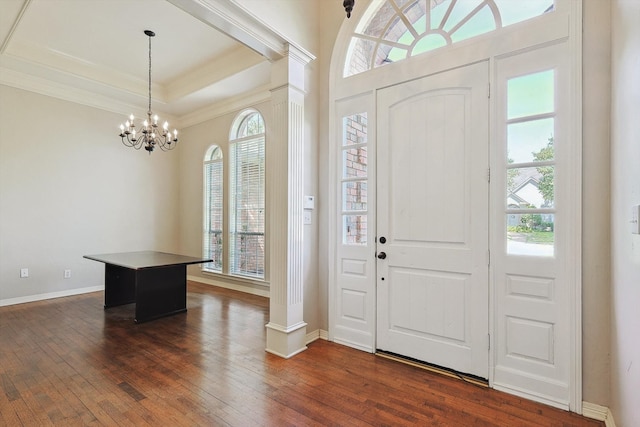 entryway featuring a raised ceiling, decorative columns, a notable chandelier, and dark hardwood / wood-style flooring