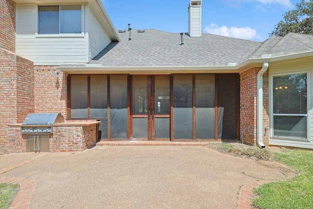 back of house featuring a patio, a sunroom, and an outdoor kitchen