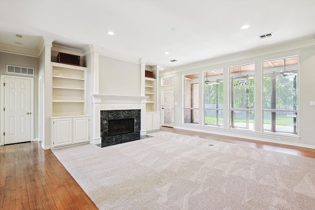 unfurnished living room with light hardwood / wood-style flooring, a premium fireplace, and ornamental molding