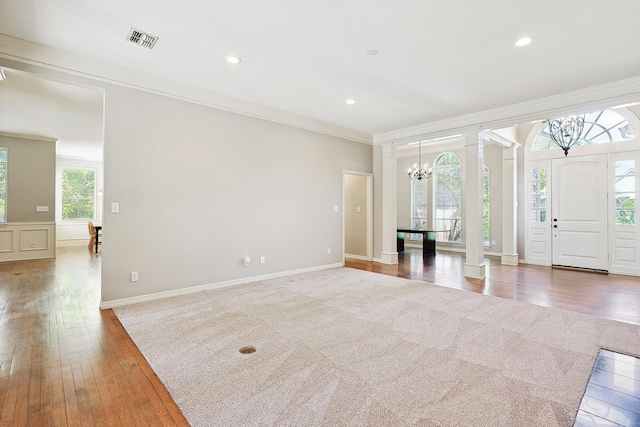 unfurnished living room with a wealth of natural light, crown molding, and hardwood / wood-style flooring