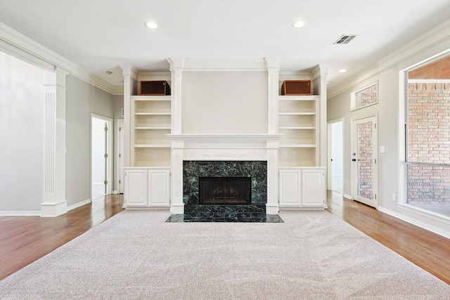 living room featuring built in features, light hardwood / wood-style flooring, ornamental molding, and a fireplace