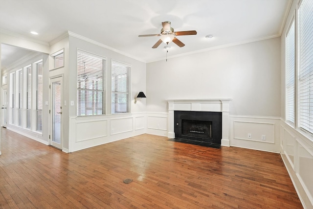 unfurnished living room with ceiling fan, a tiled fireplace, hardwood / wood-style floors, and ornamental molding